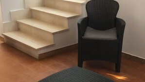 Een trap met een stoel en een poef in een kamer met betegelde vloer.