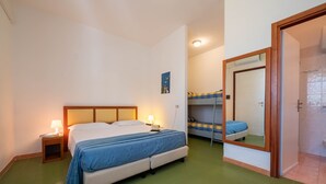 A bedroom with a bed, bedside table, lamp, bunk bed, and a mirror. - Property In A Holiday Village 'Monolocale 3 Posti Letto' with Shared Pool and Air Conditioning (peschici)