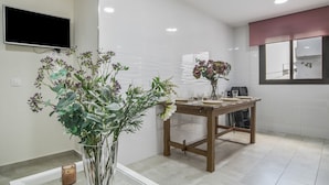 A modern kitchen with white tiles, a wooden table, and a vase of flowers. - Holiday Home 'Pepi Sánchez Conil' with Private Terrace and Wi-Fi (Conil de la Frontera)