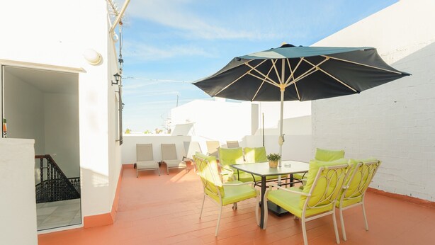 A patio with a table and chairs, a large umbrella, and a white wall. - Holiday Home 'Pepi Sánchez Conil' with Private Terrace and Wi-Fi (Conil de la Frontera)