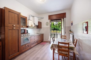 Una cocina con armarios de madera, una mesa de comedor, sillas y vistas al exterior por una ventana.