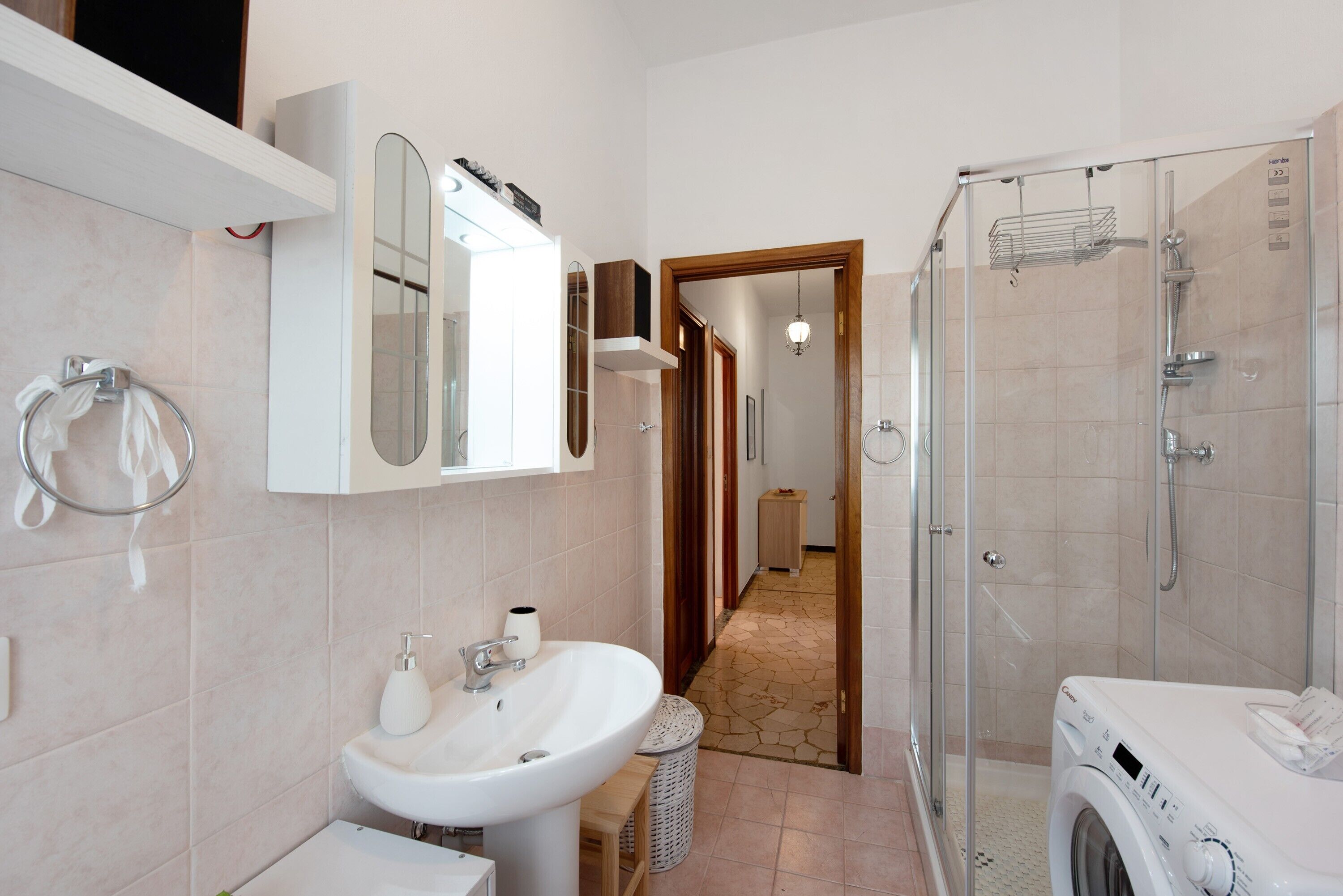 Een moderne badkamer met een wastafel, spiegel, douche en een wasmachine.