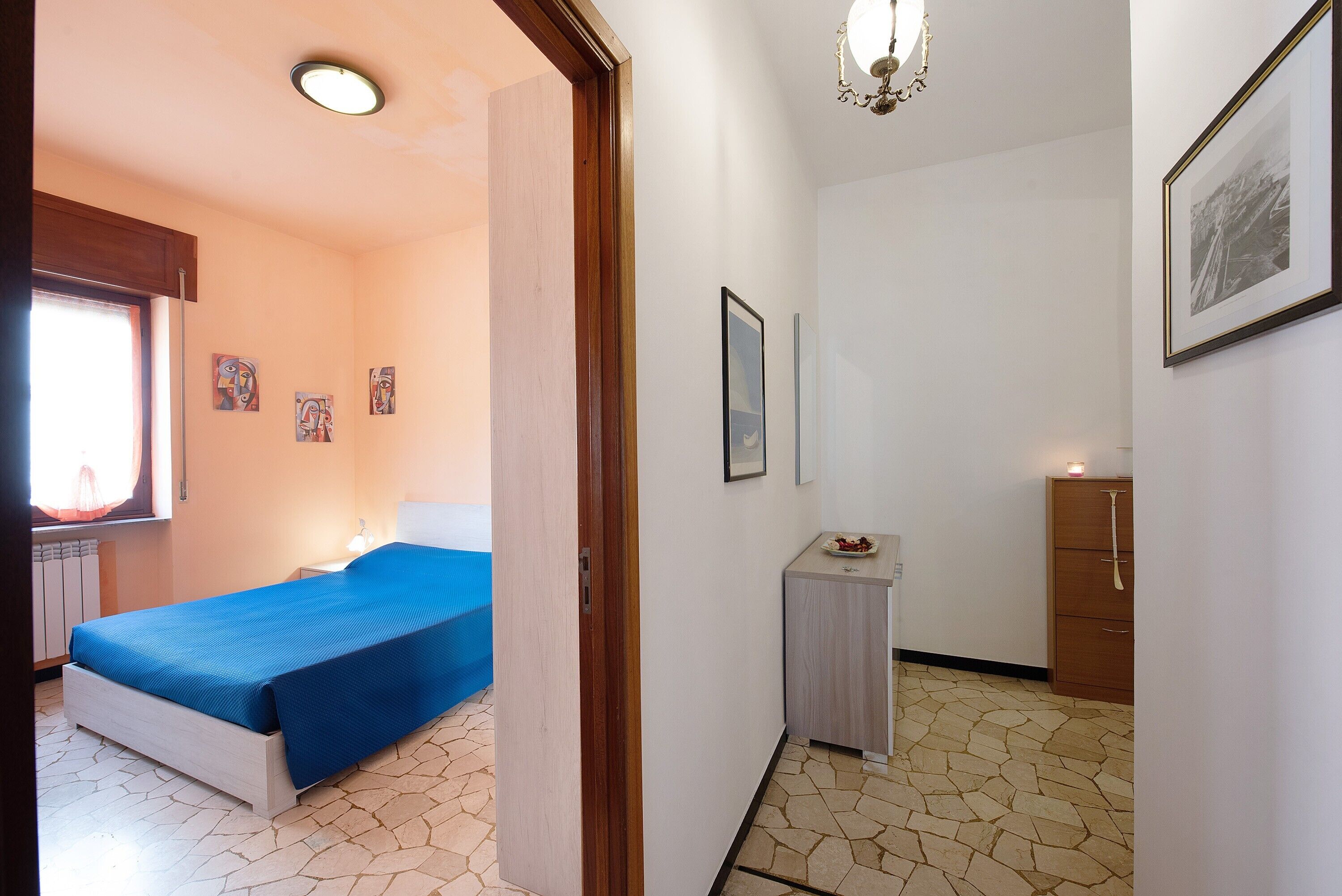 Een kamer met een bed, een klein tafeltje, een kast en een raam met gordijnen.