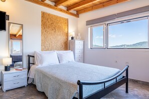 Une chambre à coucher comprenant un lit, une table de chevet, une commode, un miroir et une fenêtre donnant sur un paysage agréable.