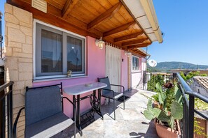 Un balcon avec une table et des chaises, un pot de fleurs et une vue sur le paysage.