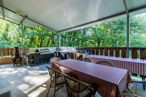 Une terrasse extérieure avec un barbecue, des tables à carreaux et des chaises en osier.