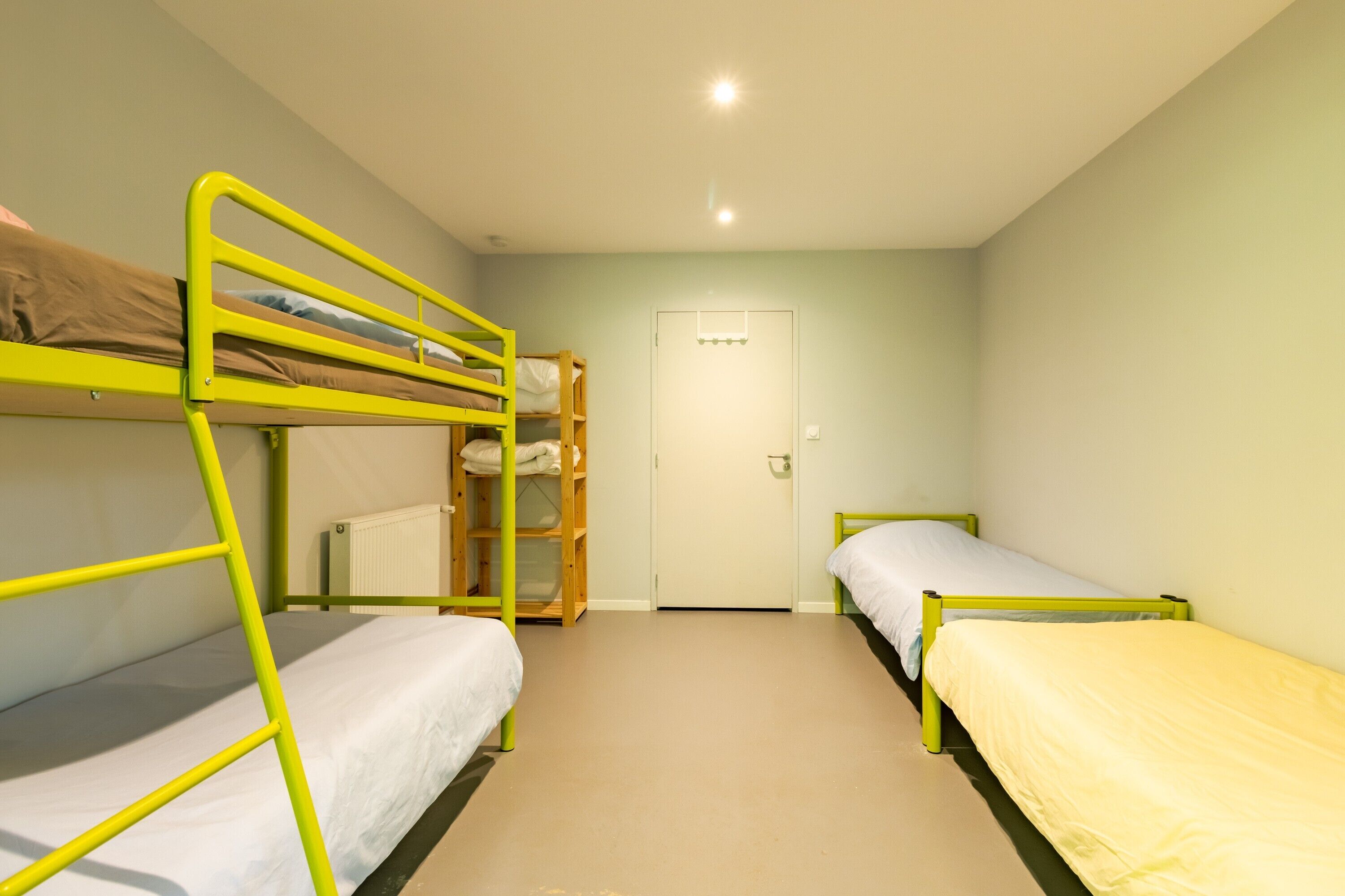 Een kamer met stapelbedden, een deur en een radiator.