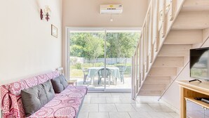 A modern living room with a sofa, a TV, and a staircase leading to an outdoor area with a table and chairs.