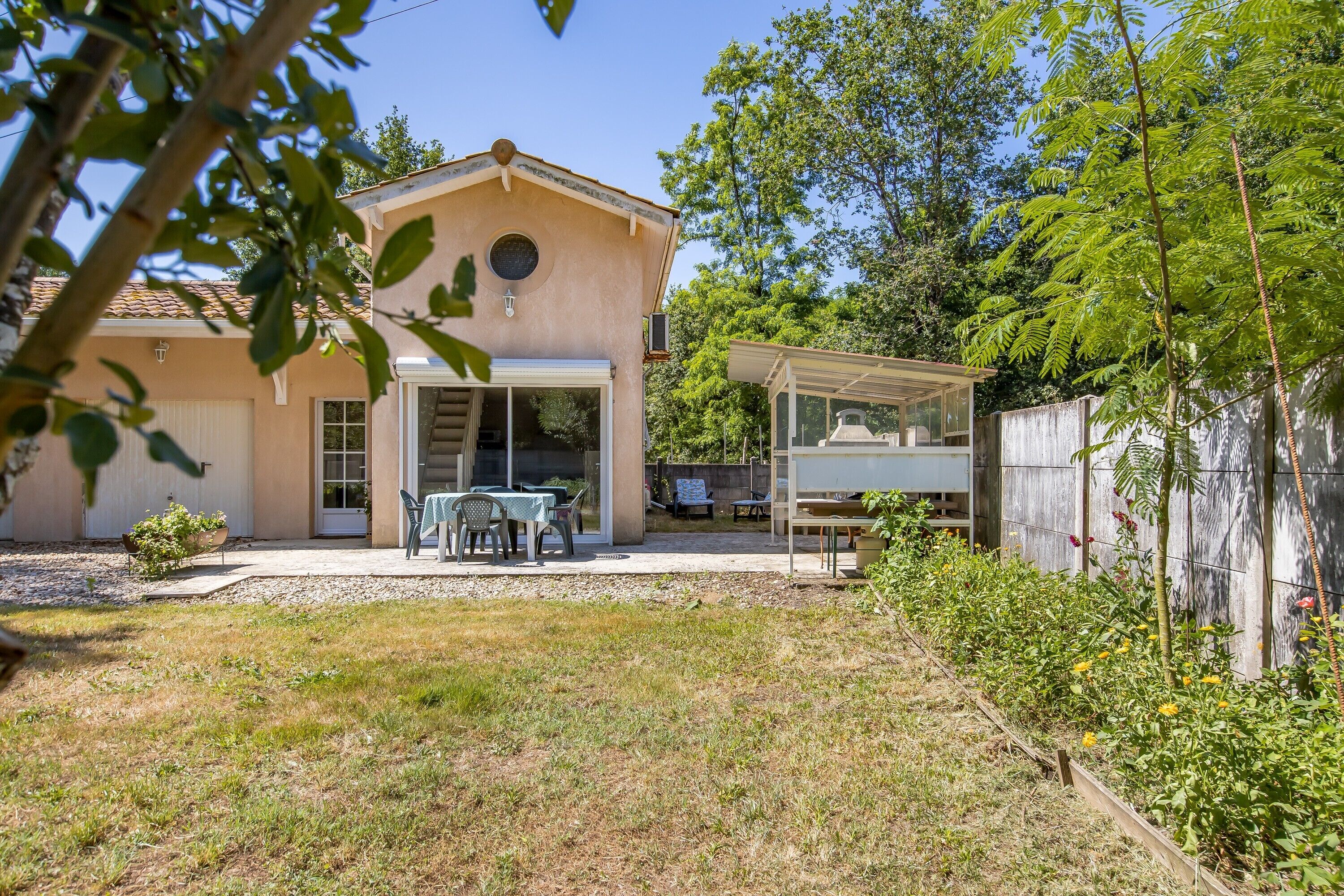 A house with a covered patio, a garage, and a garden with various plants.