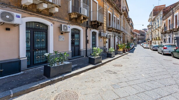 Una strada fiancheggiata da edifici storici, alcuni con balconi e condizionatori.