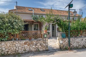 A stone-walled building with a tiled roof, a wooden fence, and a potted plant.