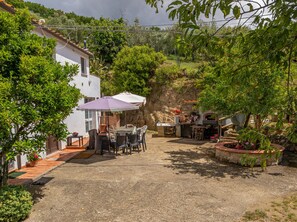 Un patio con mobiliario exterior, una mesa y una parrilla.