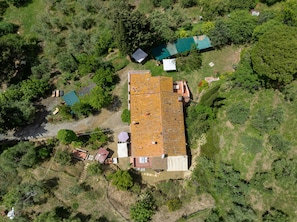 Vista aérea de una propiedad con un edificio grande, una estructura más pequeña y vegetación circundante.