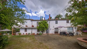 A two-story house with a patio area, outdoor furniture, and a garden.