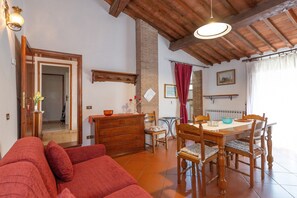 A dining area with a wooden table, chairs, and a red sofa.