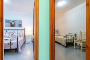 A bedroom with two beds, a nightstand, a chair, and a painting on the wall.