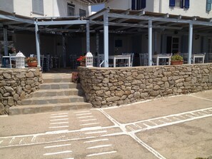 A stone wall, steps leading to a covered patio area with outdoor seating.