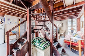 A spiral staircase with wooden beams, a bed with striped bedding, and a lamp on a side table. - Family Loft 100 Meters from the Beach, Near Arcachon Town Center (Arcachon)