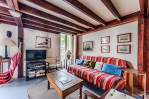 A living room with a sofa, television, wooden beams, and framed pictures on the wall. - Family Loft 100 Meters from the Beach, Near Arcachon Town Center (Arcachon)