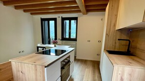 A modern kitchen with wooden flooring, a central island, and a built-in oven. - “Alpine Dream” Apartment in Valmalenco with Mountain Views and Private Garage (Caspoggio)