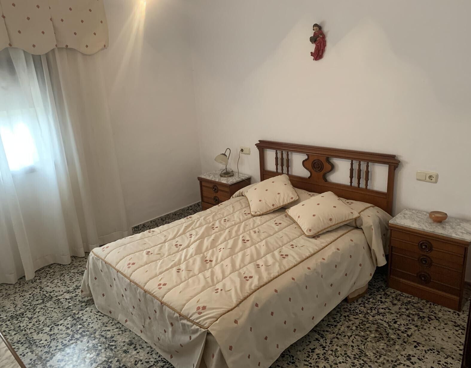A bedroom with a bed, nightstands, a lamp, and a wall decoration.