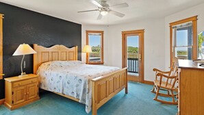 A bedroom with a bed, a nightstand, a desk, a rocking chair, and a view of the outdoors. - 8330 Mariah*DogFriendly*Hot tub*SoundViews* (Avon)