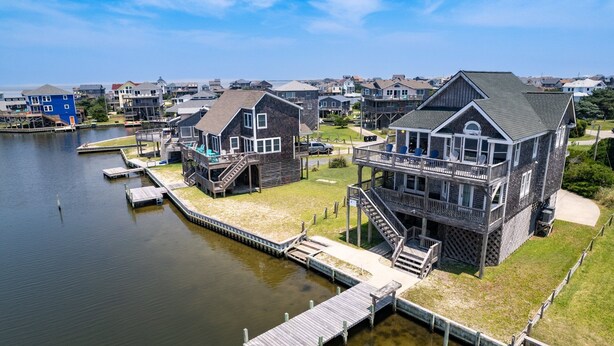 A waterfront property with multiple houses, docks, and a grassy area. - 8330 Mariah*DogFriendly*Hot tub*SoundViews* (Avon)