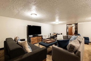 Una sala de estar con una televisión de pantalla plana, dos sofás, una mesa de centro y un comedor con una mesa y sillas.