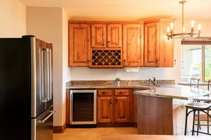 Eine Küche mit Holzschränken, einem Edelstahlkühlschrank, einem Einbauofen und einer Arbeitsplatte aus Granit.