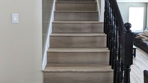 Eine Treppe mit Holzboden und schwarzen Spindeln, die zu einer Tür führt.