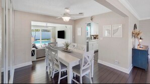 A dining area with a white table and chairs, a ceiling fan, and a view of a pool. - Pet friendly house with a heated pool and hot tub! (Deerfield Beach)
