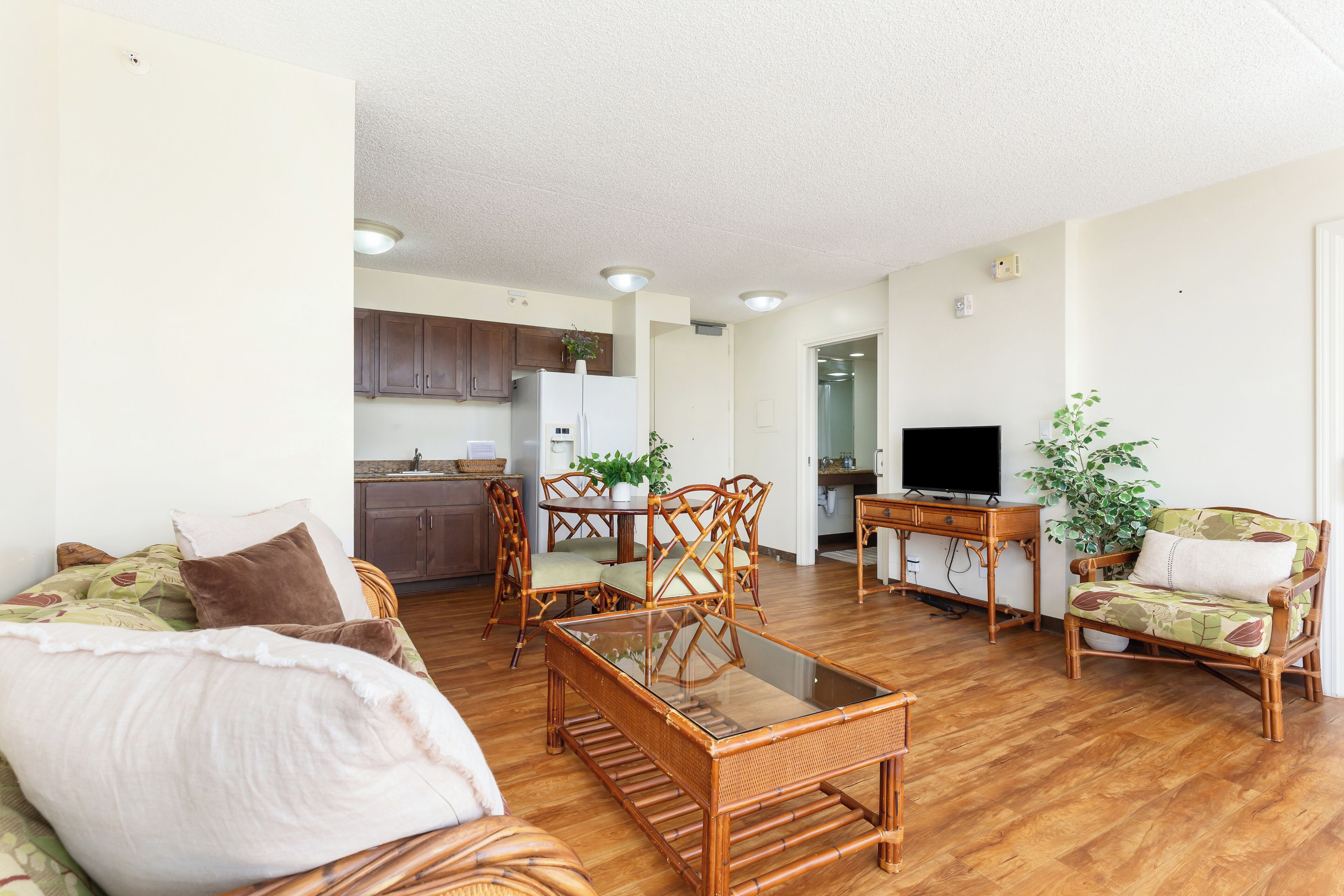 A living room with a sofa, a glass-top coffee table, and a dining area with chairs and a table.