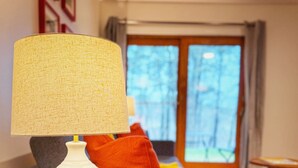 Ein Wohnzimmer mit einer weißen Lampe auf einem Holztisch, einem grauen Sofa und einem Couchtisch aus Holz.