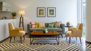 A modern living room with a sofa, two armchairs, a coffee table, and a floor lamp. There are two framed artworks on the wall and a potted plant on the side table. - El Rocio - 19 in Assagao (Assagao)