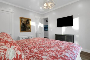 Une chambre à coucher avec un lit, une commode, un téléviseur et un tableau accroché au mur.