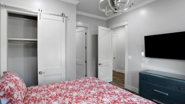 A bedroom with a bed, a dresser, a TV, and a wardrobe. - Large Group Stay | Pool + Walk to Beach (Destin)