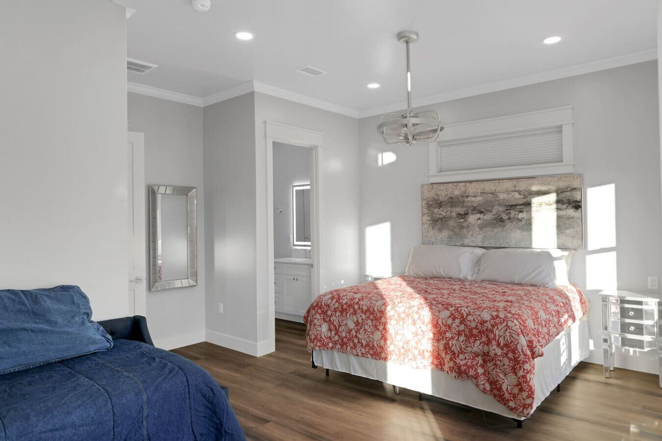 Une chambre à coucher avec un lit, une commode, un miroir et une fenêtre.
