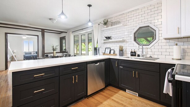 A modern kitchen with black cabinets, white countertops, and a large island. There is a dishwasher, a sink, and a window above the sink. - Secluded Retreat w/ Hot Tub, Pickleball/Basketball Court, Putting Green, Arcade (New Buffalo)
