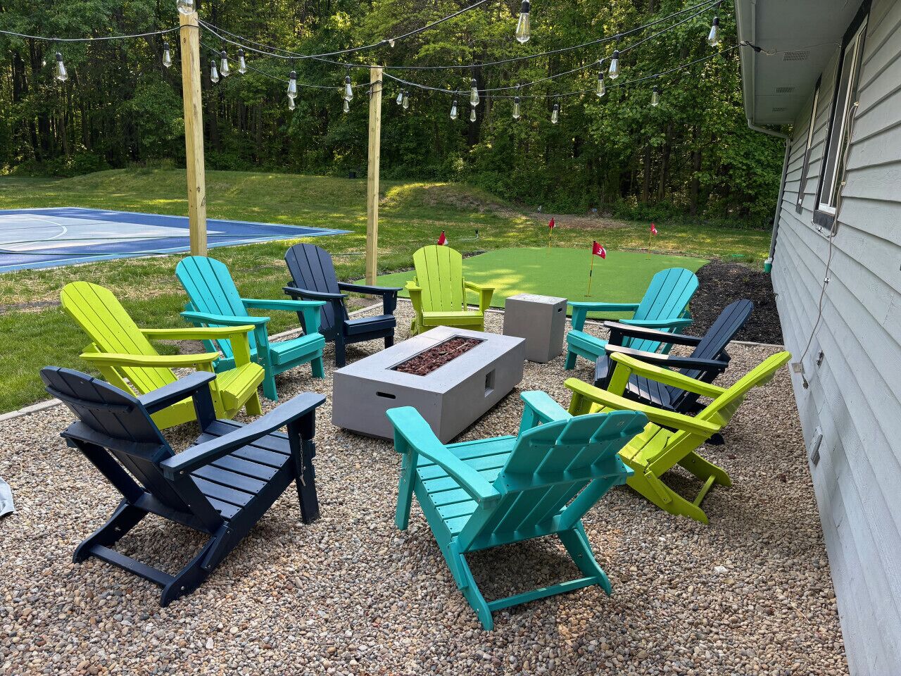 An outdoor seating area with Adirondack chairs and a fire pit.