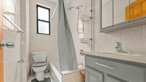 A bathroom with a toilet, shower, and vanity. - Charming 1-Bedroom apartment in Sunnyside, Queens near 40th St-Lowery St station (Queens)