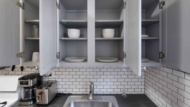 A kitchen with open cabinets, a coffee maker, a toaster, and a sink. - Charming 1-Bedroom apartment in Sunnyside, Queens near 40th St-Lowery St station (Queens)