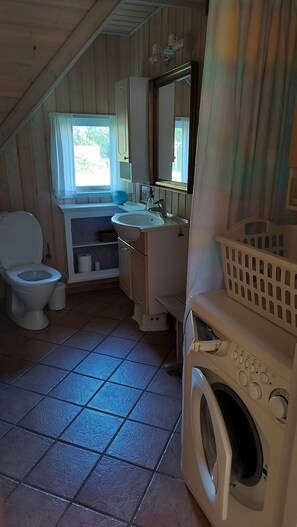 A compact bathroom with a toilet, sink, mirror, and washing machine.