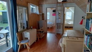 A cozy cabin with a wooden interior, a TV, a desk, a chair, a bed, and a bookshelf.