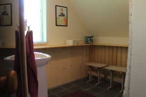 Ein Badezimmer mit einem Holzbadezimmermöbel, einem Waschbecken, einem Spiegel und einem Fenster mit Jalousien.