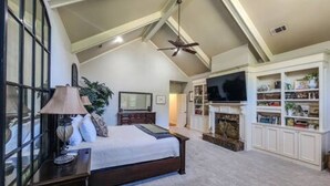 A bedroom with a large bed, a TV, a fireplace, and a bookshelf. - 6000 sq ft home with Private Pool and Hot Tub, Sleeps 16 - 13 Acres (Upatoi)