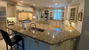A spacious kitchen with granite countertops, a central island, and built-in appliances. - 6000 sq ft home with Private Pool and Hot Tub, Sleeps 16 - 13 Acres (Upatoi)