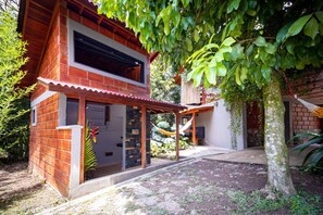 A two-story house with a brick exterior, a covered patio, and a hammock.