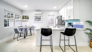 A modern kitchen with white cabinets, a central island, and bar stools. - Coastal Unit .5 Miles to Beach! (Fort Lauderdale)
