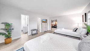 A modern hotel room with two beds, a small seating area, and a view into the kitchen. - Coastal unit! .5 miles to Beach! (Fort Lauderdale)