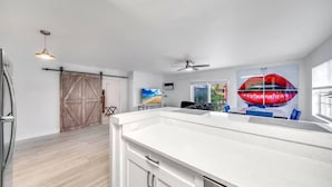 A modern kitchen with a large island, a sliding barn-style door, and a ceiling fan. - Coastal unit! .5 miles to Beach! (Fort Lauderdale)